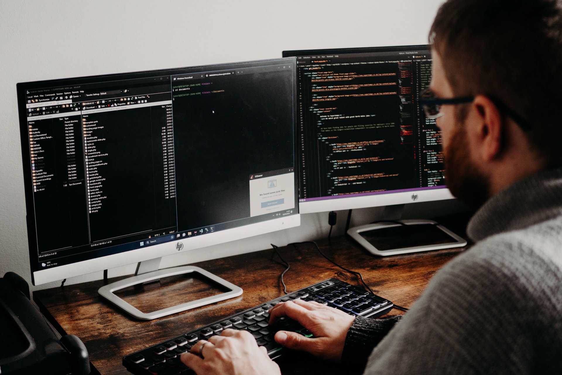 Mann an einem Arbeitsplatz mit zwei Monitoren, auf denen Programmcode zu sehen ist